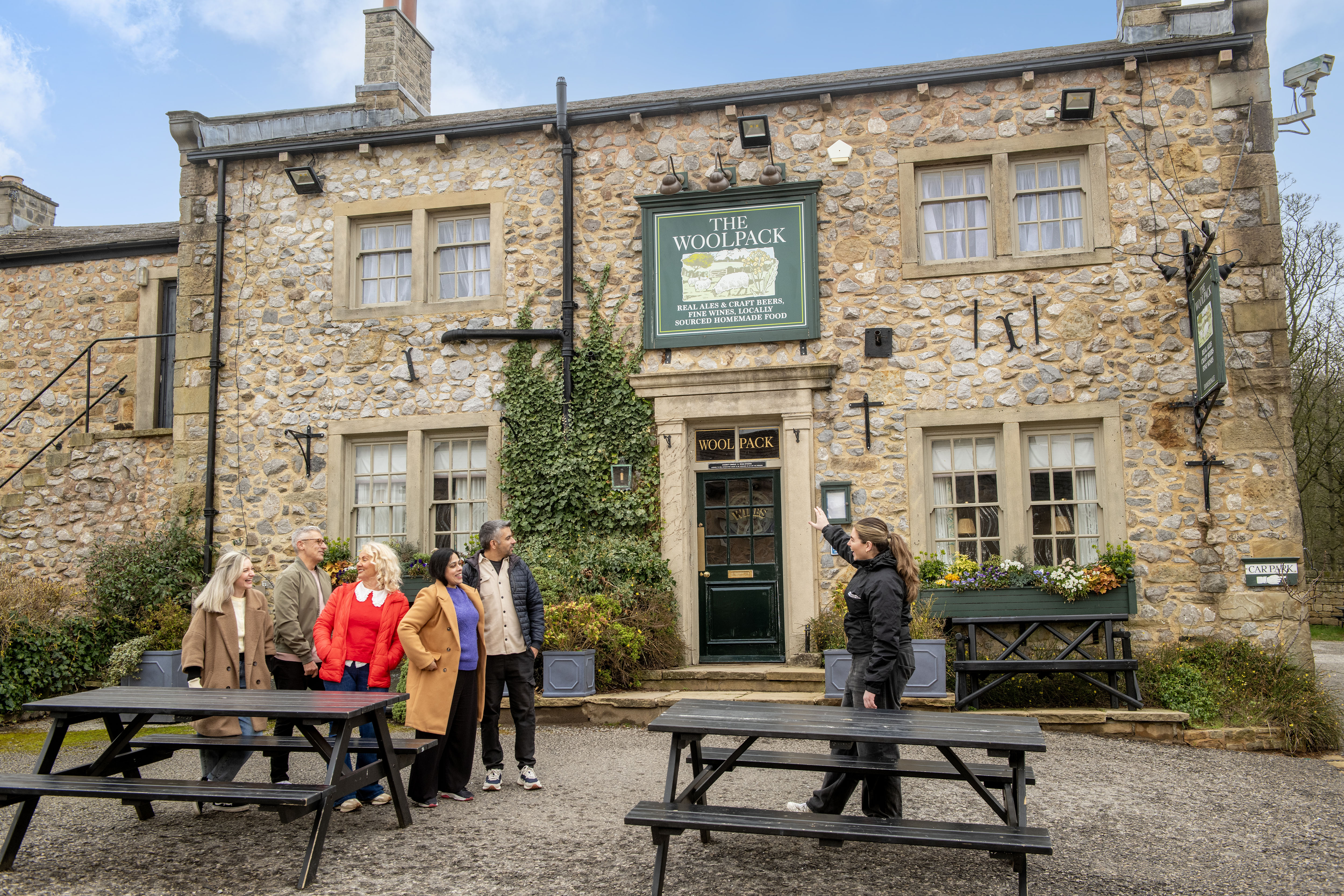 An expert guide speaking to visitors outside The Woolpack pub on Emmerdale Village Tour set